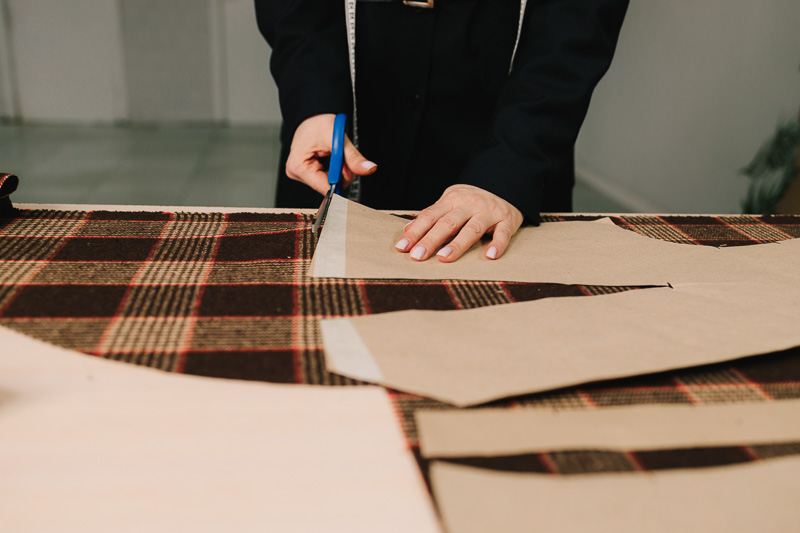 Designer cuts fabric with scissors along marked lines for precise garments and apparel